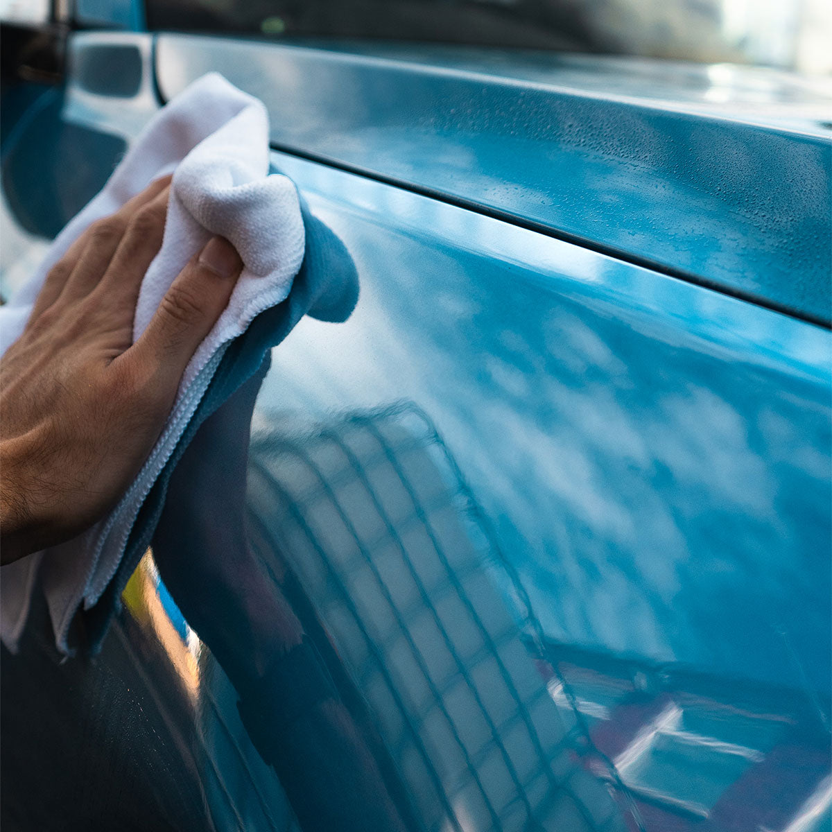 blue bmw m135i being wiped with a white microfibre cloth