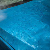 Water beading on blue car and running off