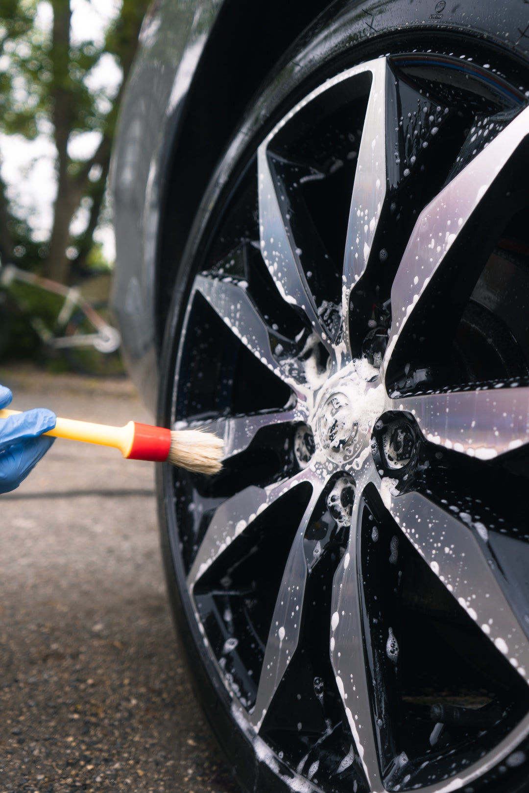 diamond cut black wheel being detailed with wheel cleaner and detailing brush