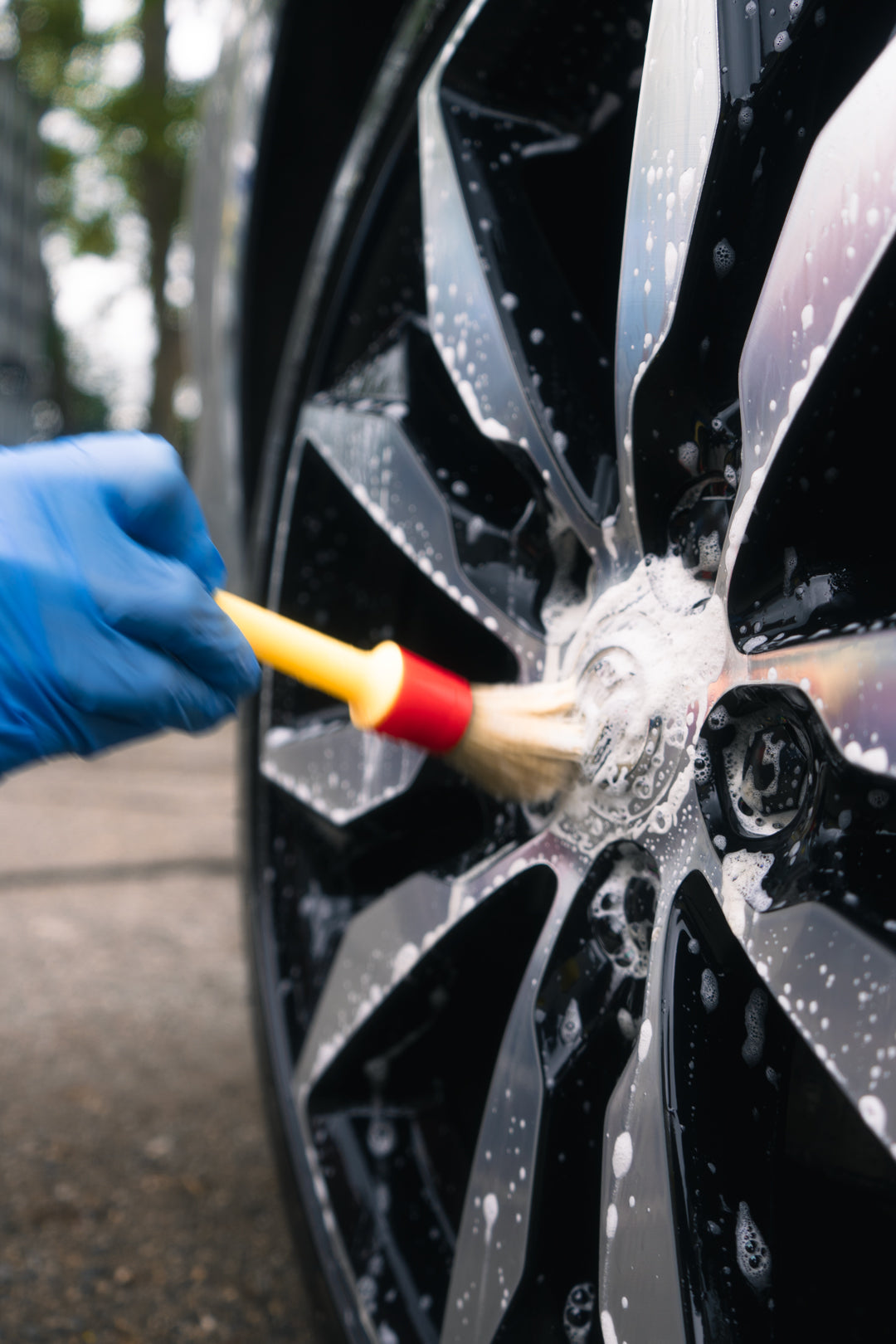 diamond cut black alloy wheel being detailed with a brush and wheel cleaner
