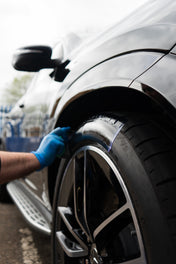 blue gloved hand applying purple tyre dressing to tyre with applicator