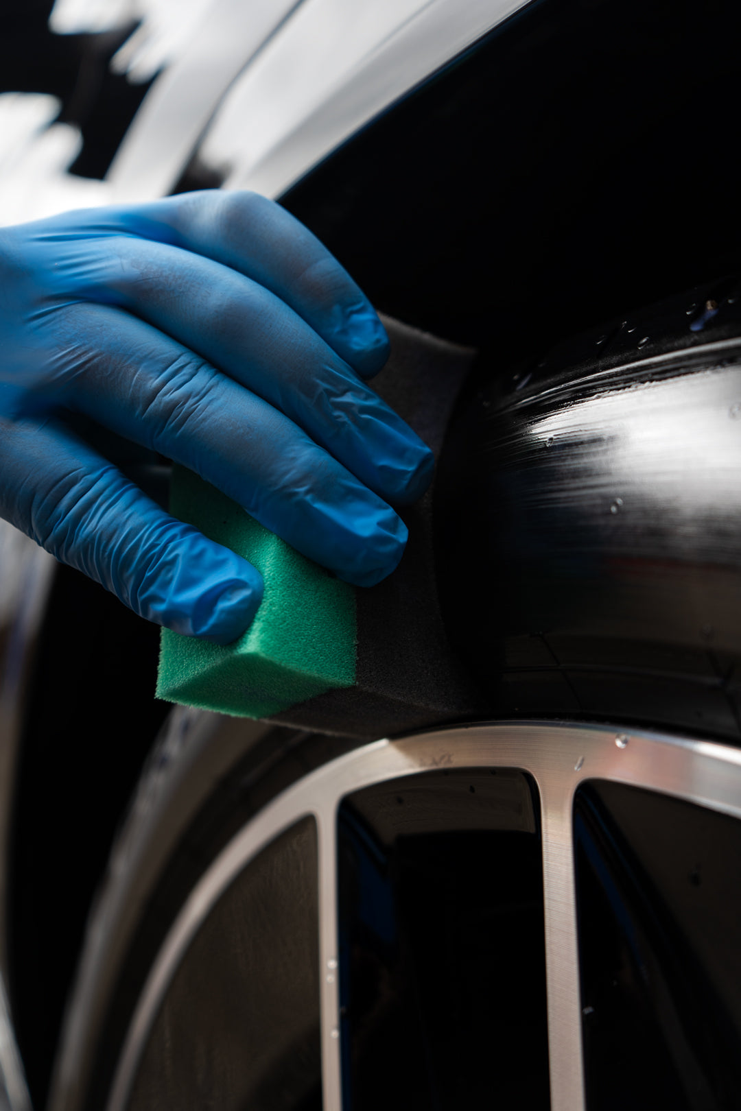 blue gloved hand applying tyre dressing to tyre with applicator