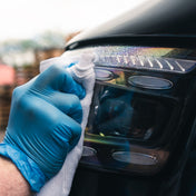 Headlight being cleaned with ceramic glass cleaner and getting wiped away