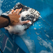 soapy soft microfibre car wash mitt on top of blue car being cleaned