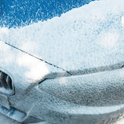 vp detailing snow foam sprayed over front of a blue bmw car being cleaned